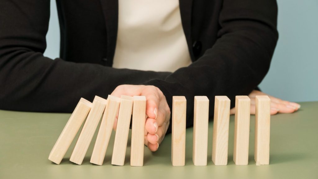 person stopping domino blocks from falling